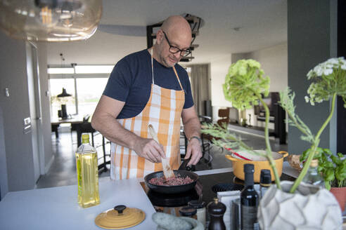 Erwachsener Mann bei der Zubereitung von Hackfleisch für eine Lasagne in seiner modernen Küche - ISF26924