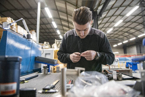 Young mechanical engineer working on steel machinery in a factory, putting together repaired equipment - ISF26925