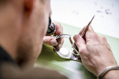Watch maker repairing a classic watch, authentic work place. Using a monocle and small tiny tools for repairs - ISF27020