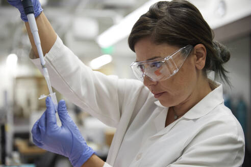 Attractive female scientist testing using test tube blood and peppet for dna results - ISF27076