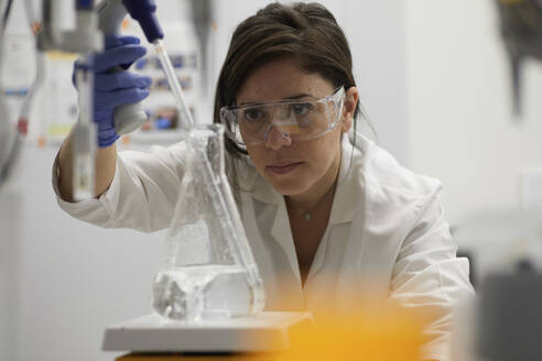 Attractive female scientist testing using beaker and peppet in labratory - ISF27084