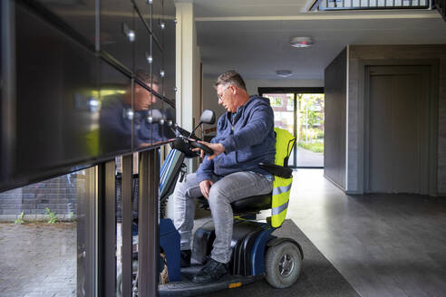 Mann im Rollstuhl verlässt seine Wohnung - ISF27122
