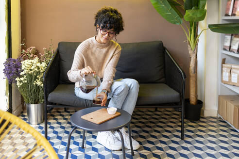 Latin woman pouring cold brew coffee into a glass on a modern geometric patterned floor. - ADSF55482