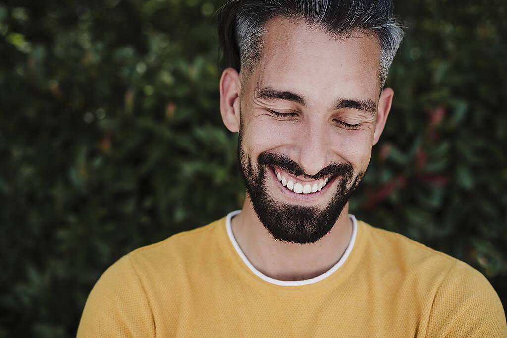 Mid adult man with eyes closed smiling at park