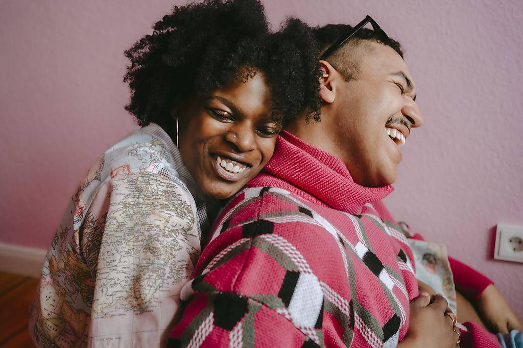 Happy hipster woman embracing gay man at home