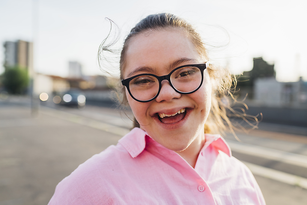 Glückliches Teenager-Mädchen mit Down-Syndrom trägt eine Brille
