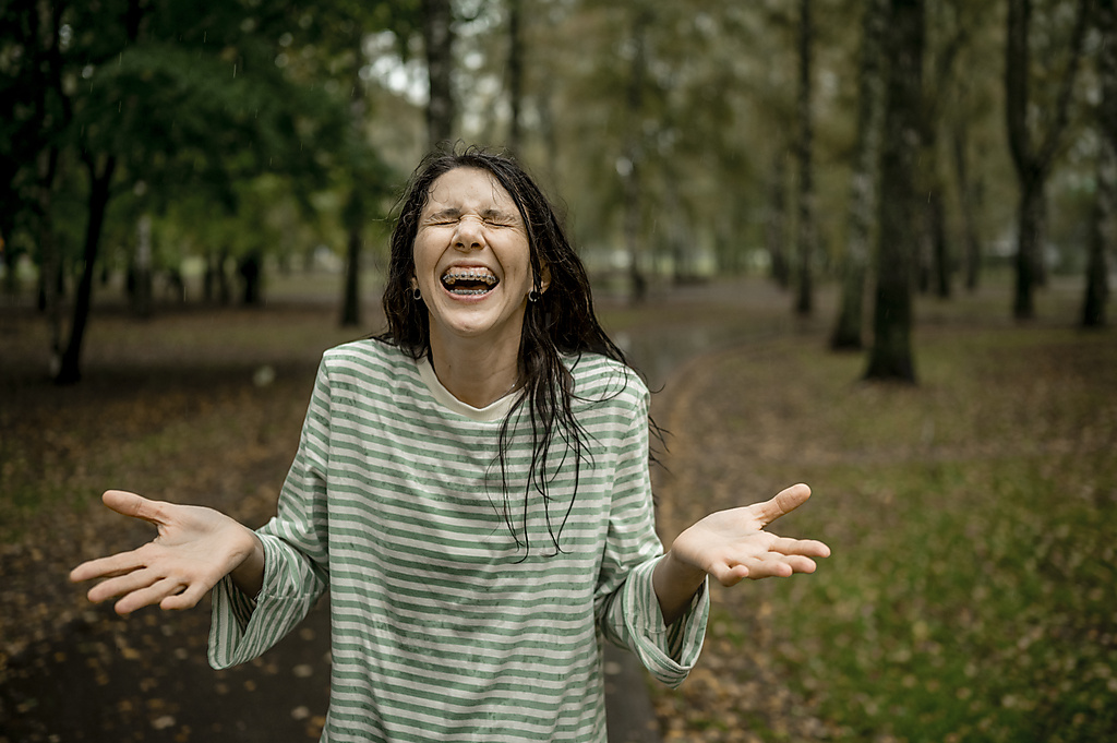 Woman with eyes closed enjoying rain in park