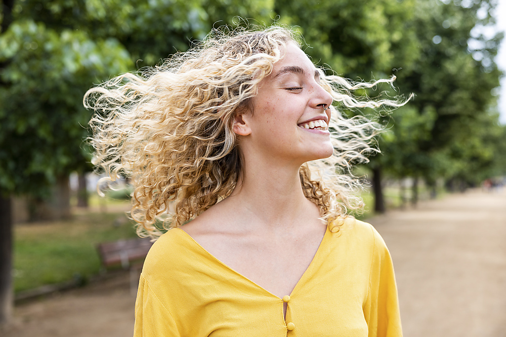 Glückliche junge Frau mit blondem Haar genießt im Park