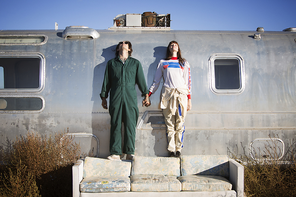 Couple holding hands while standing on sofa by trailer home